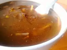 由白色碗承装,汤呈棕黄色,内有牛肉、粉条等食物