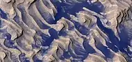 丹尼尔森陨击坑地面上的岩层和黑色尘埃彩色近景图，可在图像中看到巨岩。