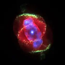 類似貓眼睛組織的影像。一個明亮的白點描繪出針尖大小的中央恆星,幾乎就精確地位於影像的中心。中央恆星由在三度空間呈橢圓形,表面有著不規則邊緣的殼層區域包圍著。這是一個被有著黃色和綠色邊緣包覆疊加的紅色的區域,暗示有著另一個三度空間的殼層。