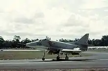 一張白色軍事噴氣式戰鬥機沿著跑道滑行的彩色照片。