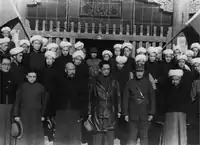 1934年，宋子文、马步芳在青海西宁的清真寺前，与当地男性回族民众合影。男性民众穿着的长袍马褂是当时中国男性普遍的着装。同时，他们以佩戴白色缠头的方式，展示穆斯林身份。